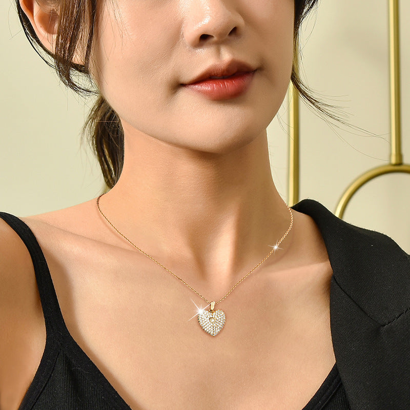 Close-up of a person wearing a gold necklace with a heart-shaped pendant.