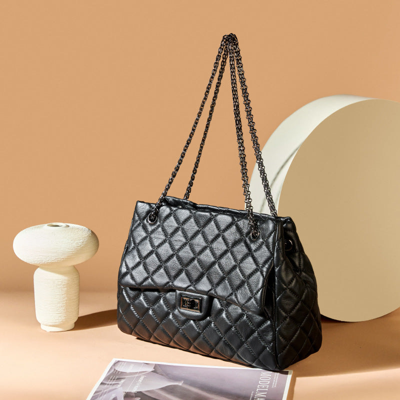 Black quilted handbag with chain strap on a beige background