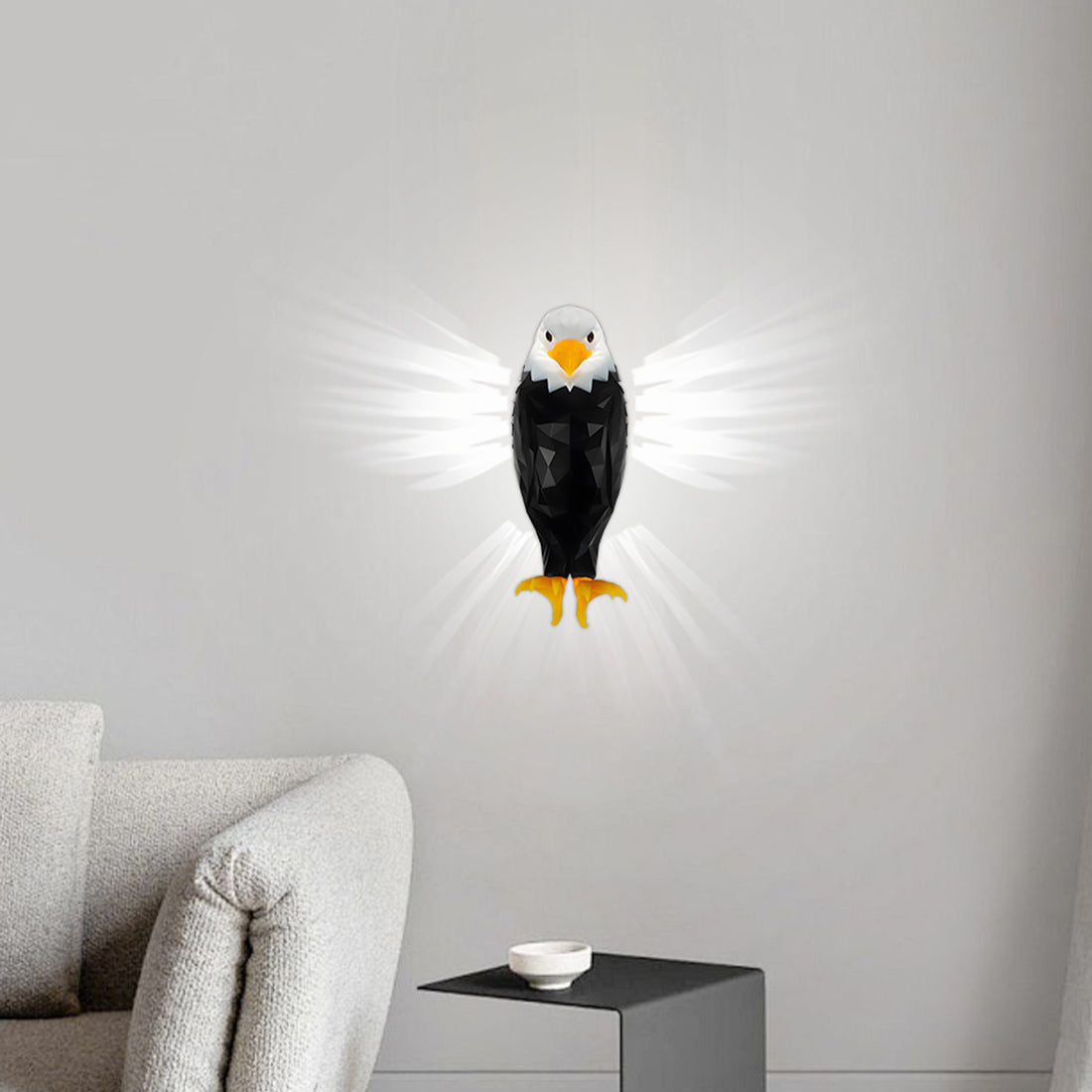 A wall-mounted eagle night light with glowing white wings, shown lit on a light gray wall above a sofa in a modern living room setting.