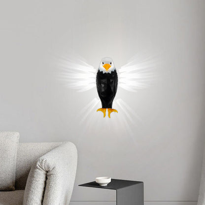 A wall-mounted eagle night light with glowing white wings, shown lit on a light gray wall above a sofa in a modern living room setting.