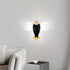 A wall-mounted eagle night light with glowing white wings, shown lit on a light gray wall above a sofa in a modern living room setting.