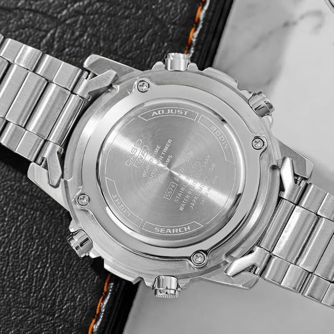 Close-up of a silver watch with a detailed backplate on a textured surface.