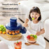 Child eating a bowl of fruit salad with a smoothie maker and fruits on a table.
