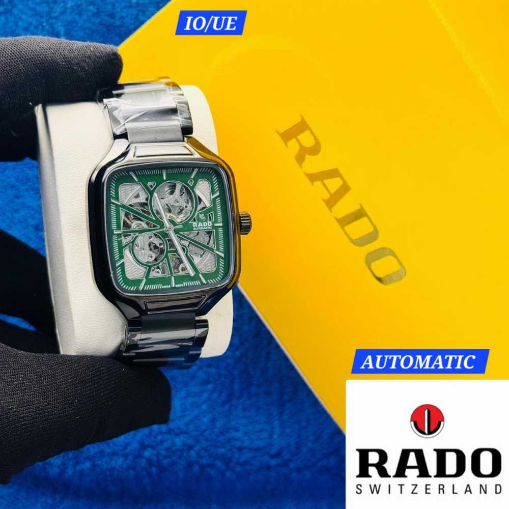 Rado watch held by a gloved hand with a yellow and blue background