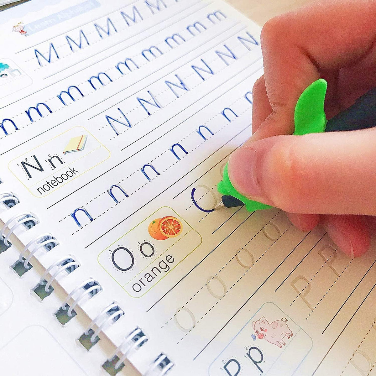 Handwriting practice book with letters and a hand using a green pen to write.