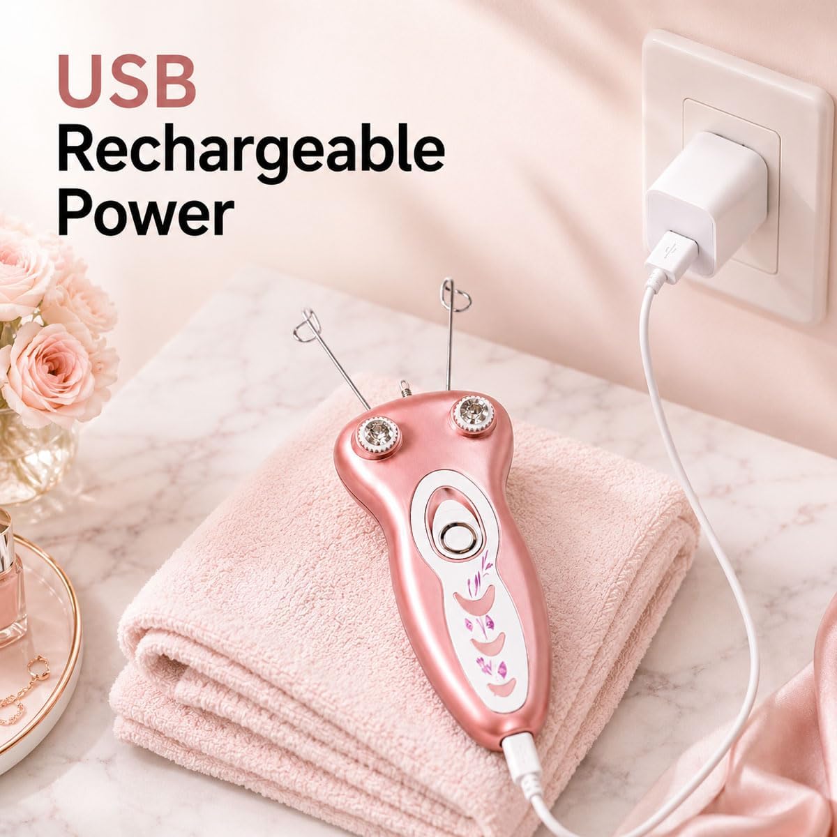 A pink USB rechargeable beauty device with two metal needle-like attachments rests on folded pink towels on a marble surface, with a wall outlet and plug connected. Text reads &