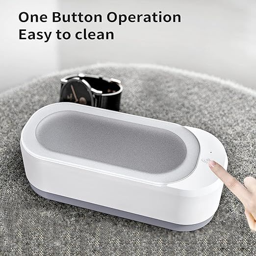 White electronic device with a gray interior on a textured surface, featuring text &