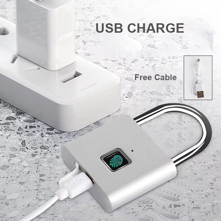 A silver USB charging lock with a fingerprint sensor and black shackle, shown plugged into a white wall charger. The image includes text reading &