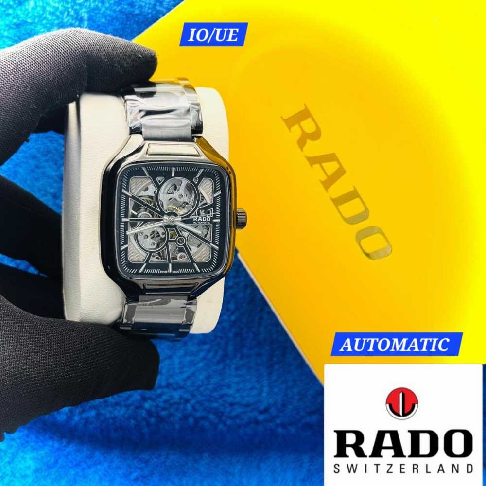 Rado watch held by a gloved hand with a yellow and blue background