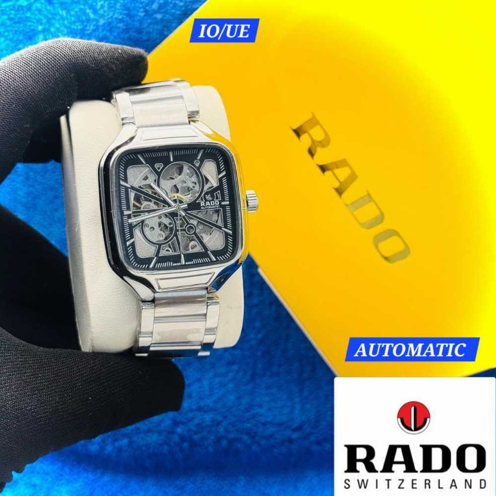 Rado watch held by a gloved hand with a blue and yellow background