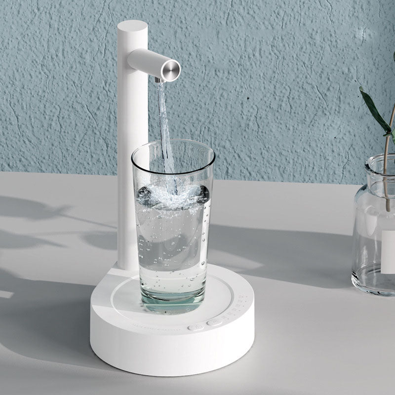 White manual water pump filling a glass with water on a light gray surface.