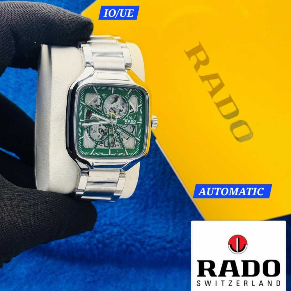 Rado watch held by a gloved hand with a yellow and blue background